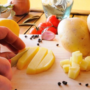 Chef Cutting Potatoes On A Cutting Board In The Kitchen