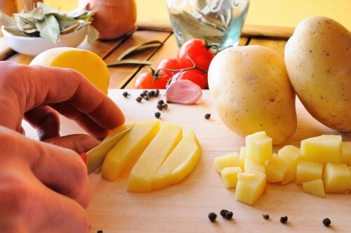 Chef Cutting Potatoes On A Cutting Board In The Kitchen