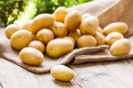 Farm fresh baby potatoes displayed on a hessian sack on a rustic wooden table at farmers market a healthy nutritious root vegetable popular in vegetarian and vegan cuisine
** Note: Shallow depth of field