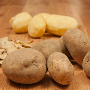 White peeled potatos. Potato peelings.  Next to are peelings